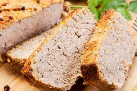 Domowy pasztet według starego przepisu, pokrojony w plastry, z przyprawami i natką pietruszki.
