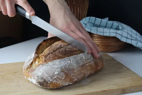 Krojenie świeżo upieczonego chleba na desce. Idealny przepis na chleb dla każdego.