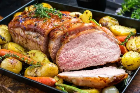 Soczysta polędwica wieprzowa z piekarnika, pieczona z ziemniakami, marchewką i cebulą. Aromatyczne zioła podkreślają smak dania.