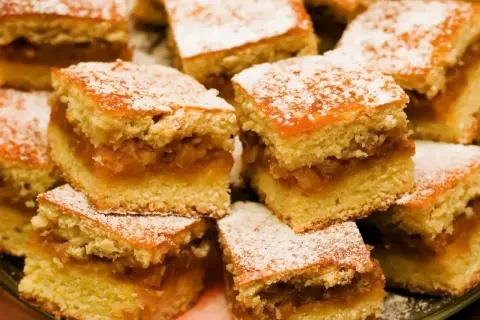Pyszne ciasto z jabłkami, pokrojone w kostkę i posypane cukrem pudrem. Idealne na deser!