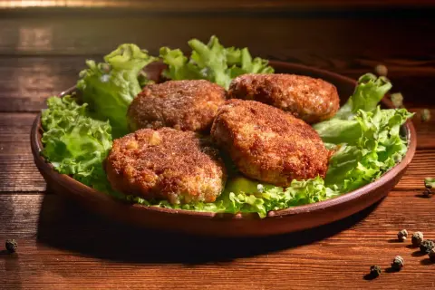 Cztery soczyste mielone z air fryer, podane na liściach sałaty, kuszą apetycznym wyglądem.