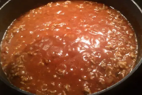 Gęsty, aromatyczny sos do spaghetti z mielonym mięsem, gotujący się w garnku.