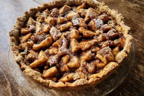 Apetyczna tarta na słodko z jabłkami i kruszonką, posypana cukrem pudrem. Idealna na deser.