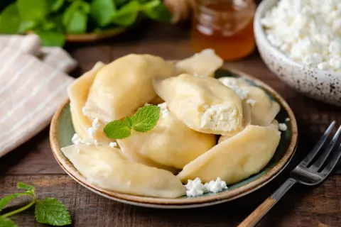 Pyszne pierogi z serem na słodko, posypane twarogiem i udekorowane miętą. Idealne na deser.