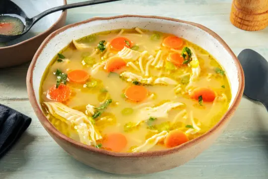 A miseczce paruje aromatyczna zupa z kurczakiem, pełna makaronu, marchewki i zielonej pietruszki. Idealna na chłodne dni.