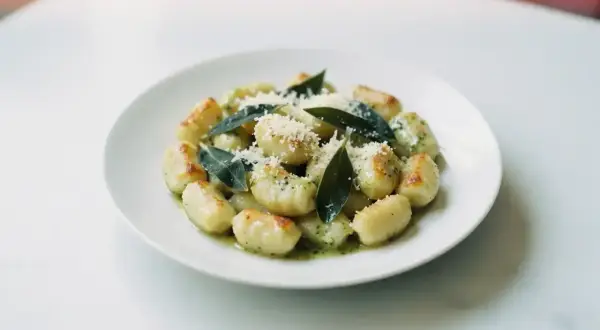 Pyszne gnocchi z sosem, posypane parmezanem i ozdobione listkami szałwii. Idealne danie dla miłośników włoskich smaków.
