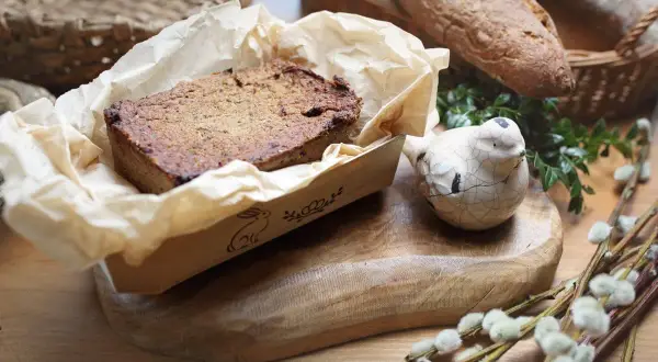 Domowy pasztet z królika w papierowej foremce, obok ceramiczny ptaszek i chleb.
