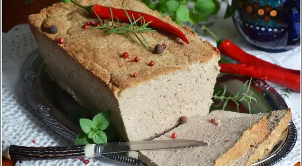 Pyszny pasztet mieszany drobiowo-wieprzowy, udekorowany papryczką chili i ziołami, gotowy do podania na kromkach chleba.