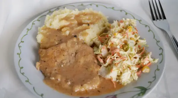 Pyszny schab w sosie podany z puree ziemniaczanym i chrupiącą surówką z kapusty i marchewki. Idealny obiad.