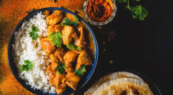Aksamitny butter chicken przepis z ryżem i plackami naan. Aromatyczne przyprawy i świeża kolendra dopełniają danie.