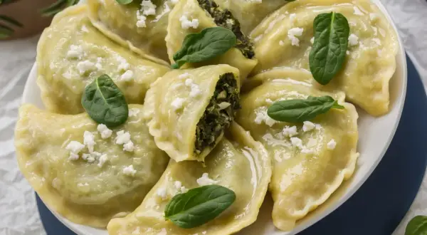Pyszne pierogi ze szpinakiem i fetą, udekorowane świeżymi listkami szpinaku.