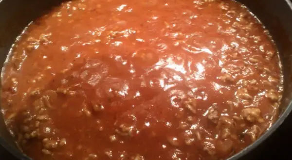 Gęsty, aromatyczny sos do spaghetti z mielonym mięsem, gotujący się w garnku.