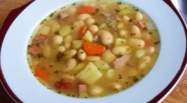 Pyszna zupa fasolowa przepis babci. Biała fasola, ziemniaki, marchewka i kawałki wędzonki w aromatycznym bulionie.