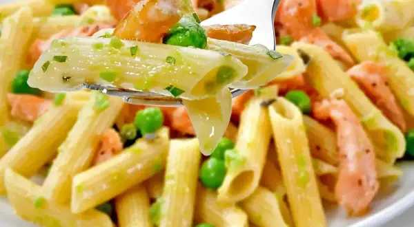 Penne z łososiem wędzonym i groszkiem na widelcu. Pyszne danie, które zachwyci każdego smakosza.