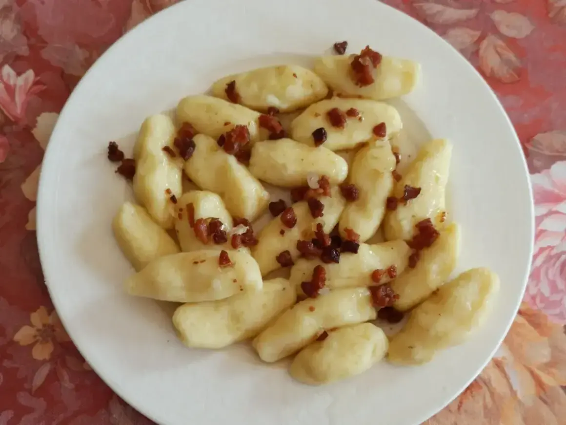 Kopytka z boczkiem, jak u babci! Pyszne ciasto na kopytka przepis babci, podane na białym talerzu.