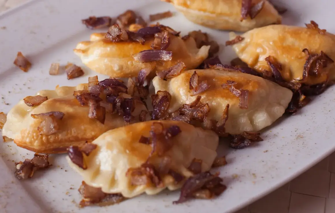 Pyszne pierogi z mięsem, posypane chrupiącą cebulką, kuszą swoim wyglądem.