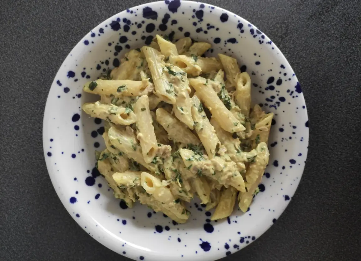 Penne z kremowym sosem, tuńczykiem i natką pietruszki w talerzu w granatowe cętki. Pyszny makaron z tuńczykiem.