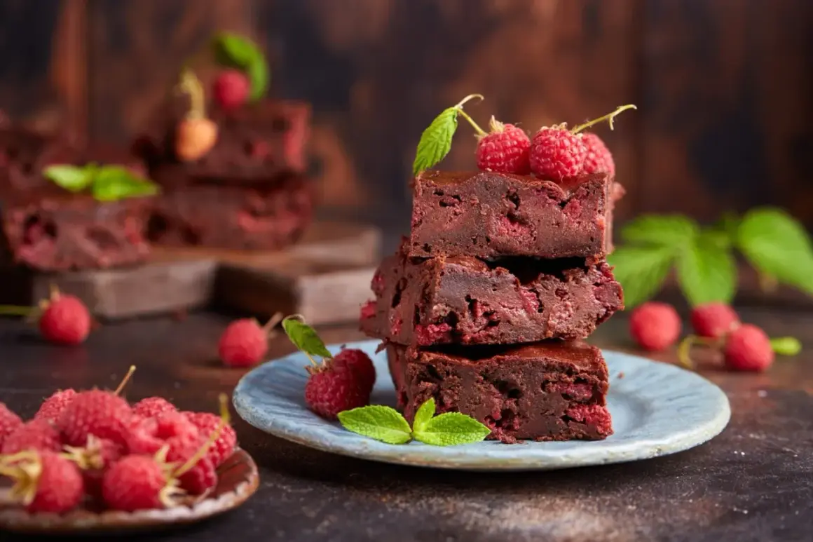 Stos pysznych brownie z malinami, ozdobiony świeżymi malinami i listkami mięty.