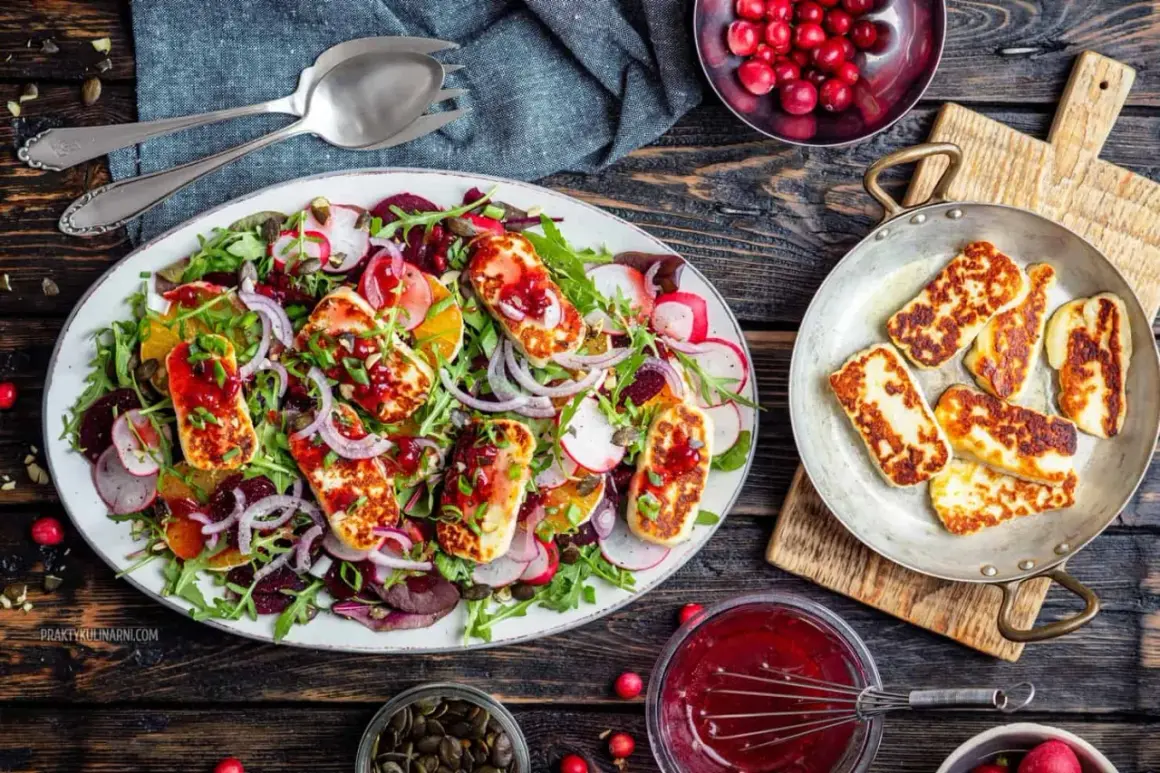 Kolorowa sałatka z grillowanym halloumi, burakami, pomarańczą i rukolą, polana sosem żurawinowym.