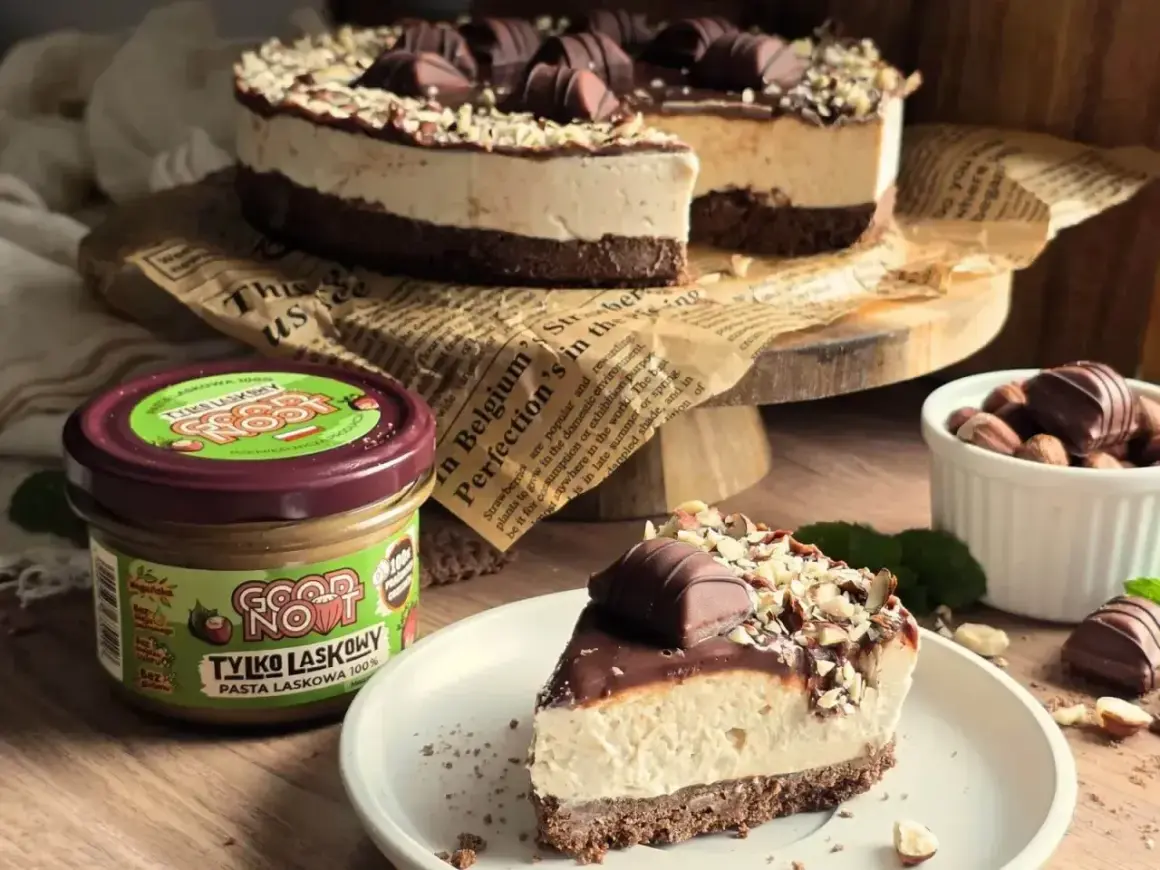 Pyszne ciasto Kinder Bueno z kremem i orzechami, obok słoik pasty z orzechów laskowych.