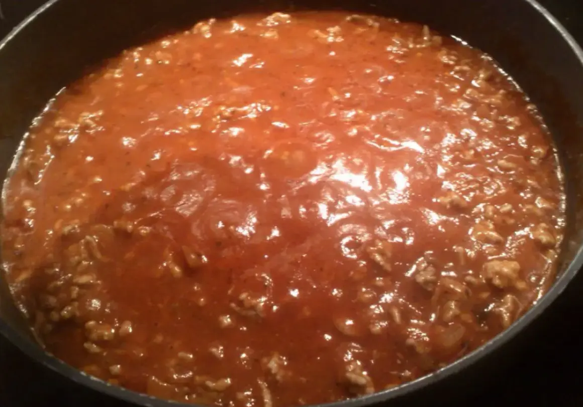Gęsty, aromatyczny sos do spaghetti z mielonym mięsem, gotujący się w garnku.