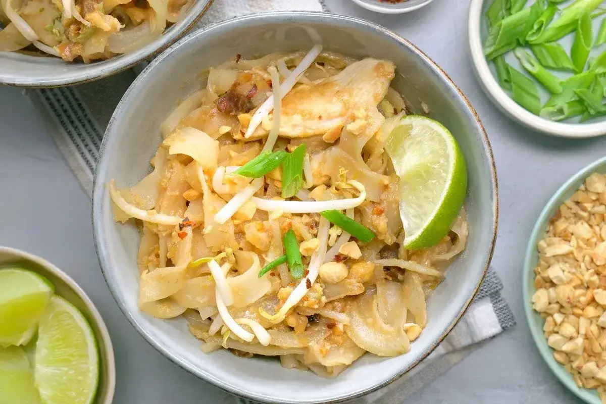 Pyszny pad thai z kurczakiem, makaronem ryżowym, kiełkami, orzeszkami i limonką.