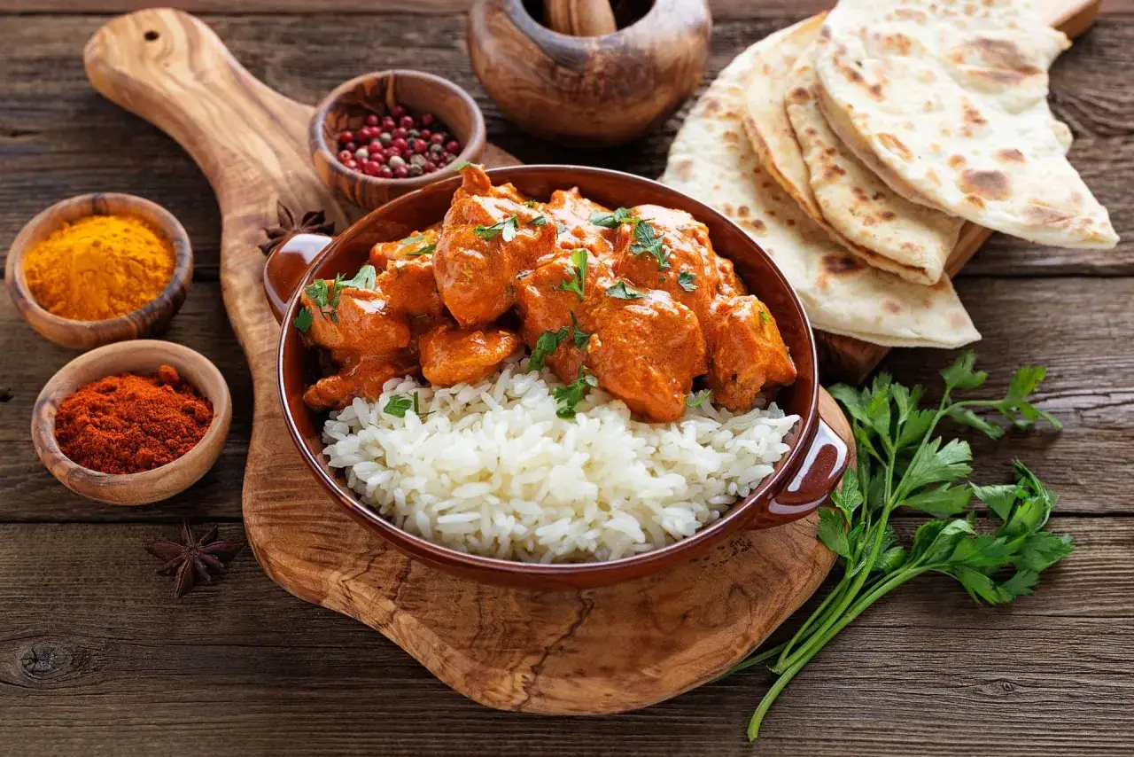 Pyszne chicken tikka masala z ryżem, podane z plackami naan i przyprawami.