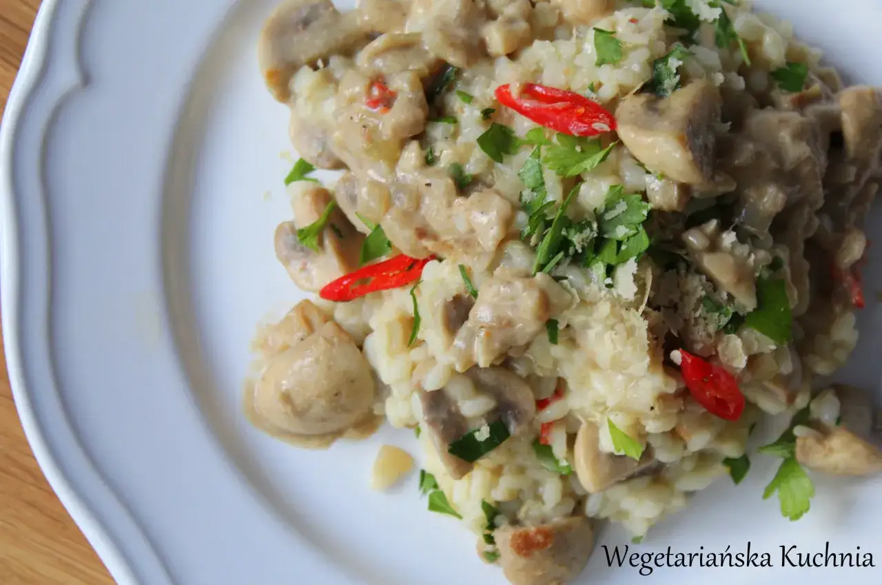 Kremowe risotto z pieczarkami, ozdobione natką pietruszki i papryczką chili. Idealne danie dla miłośników wegetariańskiej kuchni.
