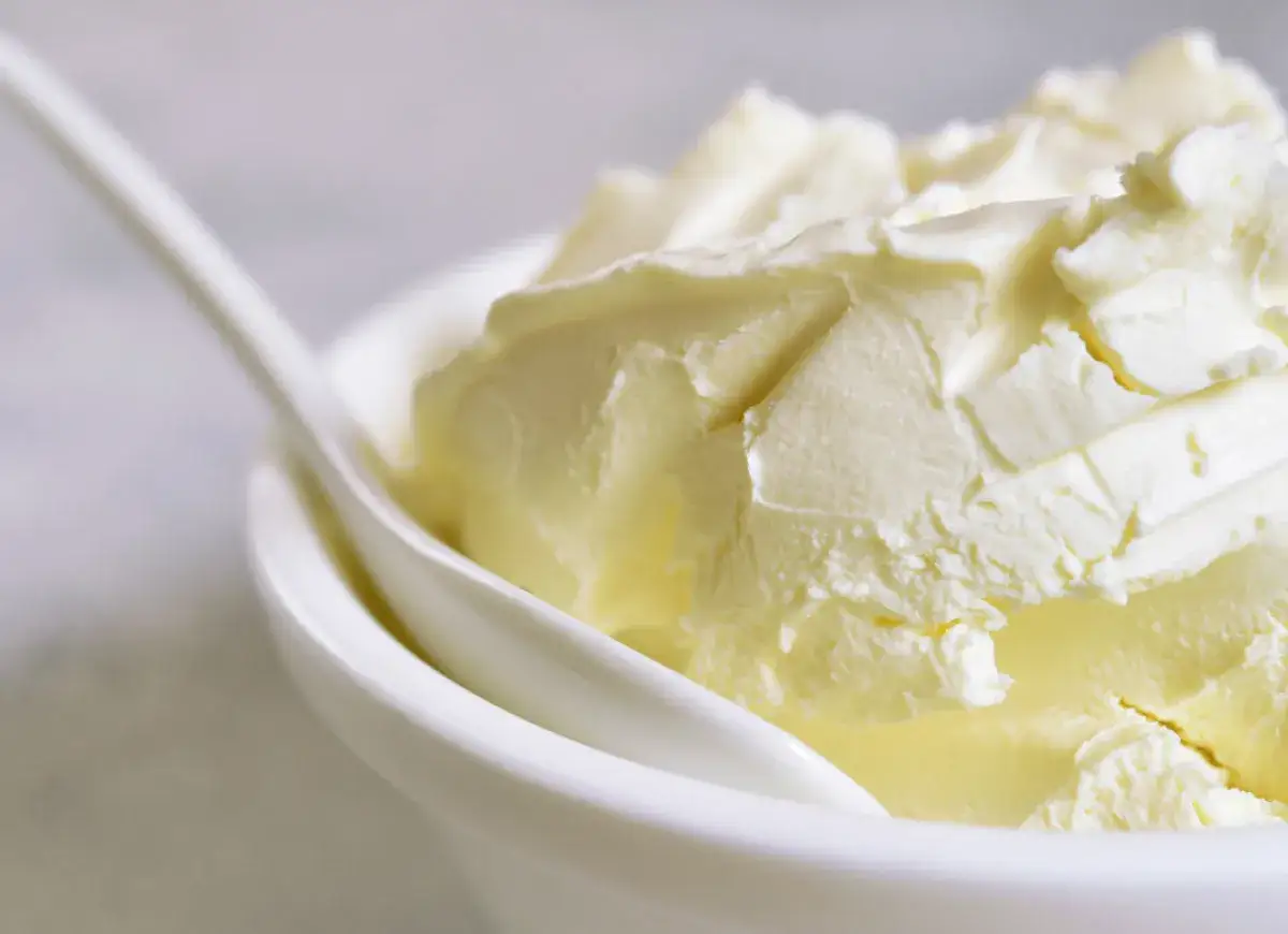 Kremowa masa w miseczce, idealna jako zamiennik mascarpone do deserów. Biała łyżeczka zanurzona w kremie.