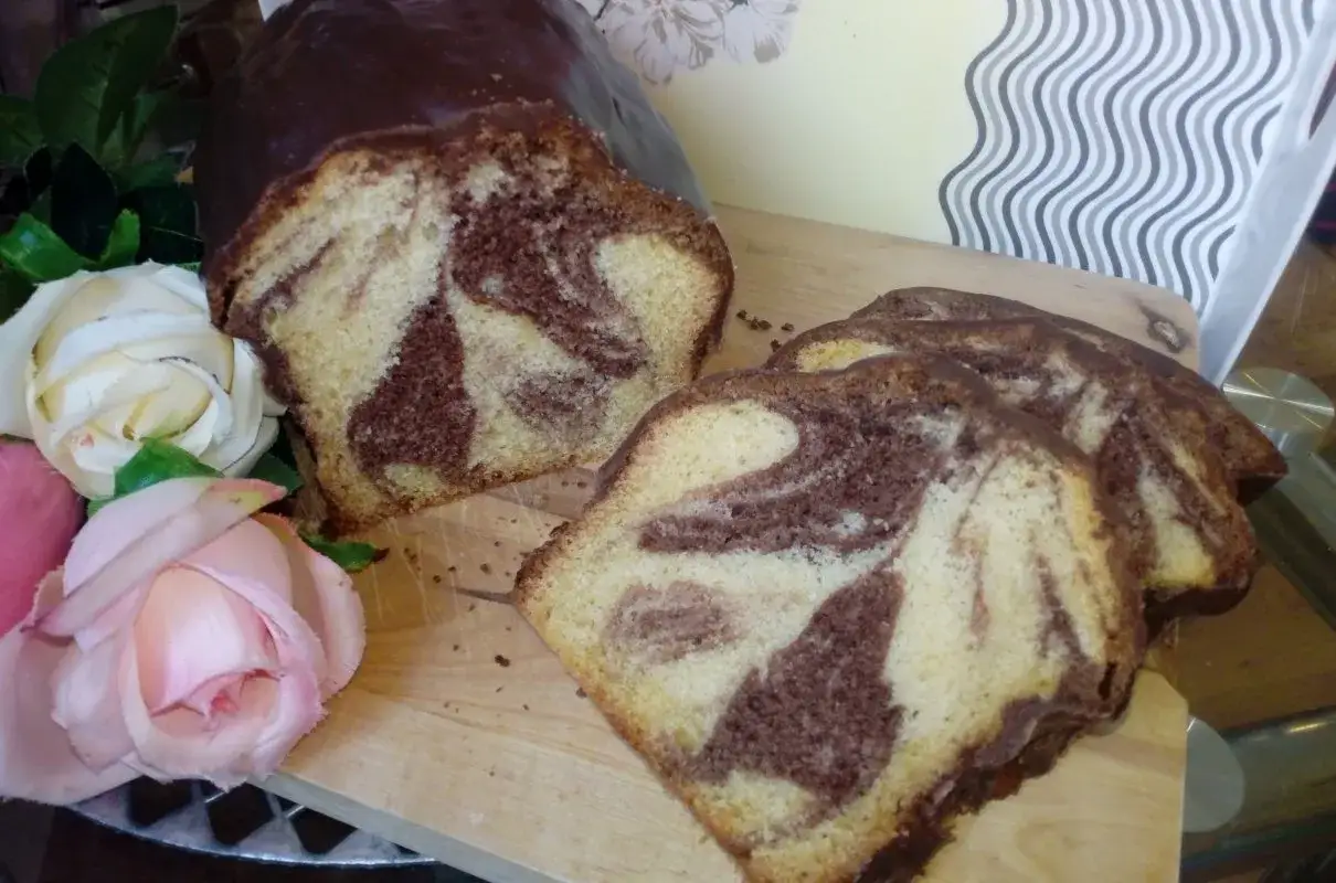 Szybka babka wilgotna z polewą czekoladową i marmurkowym wnętrzem, ozdobiona różami.