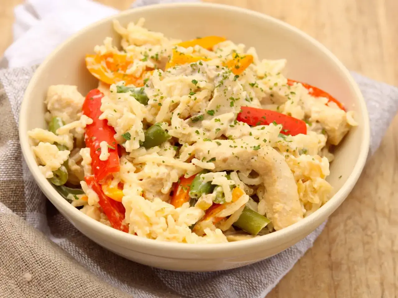 Pyszne risotto z kurczakiem, papryką i fasolką szparagową, posypane natką pietruszki.