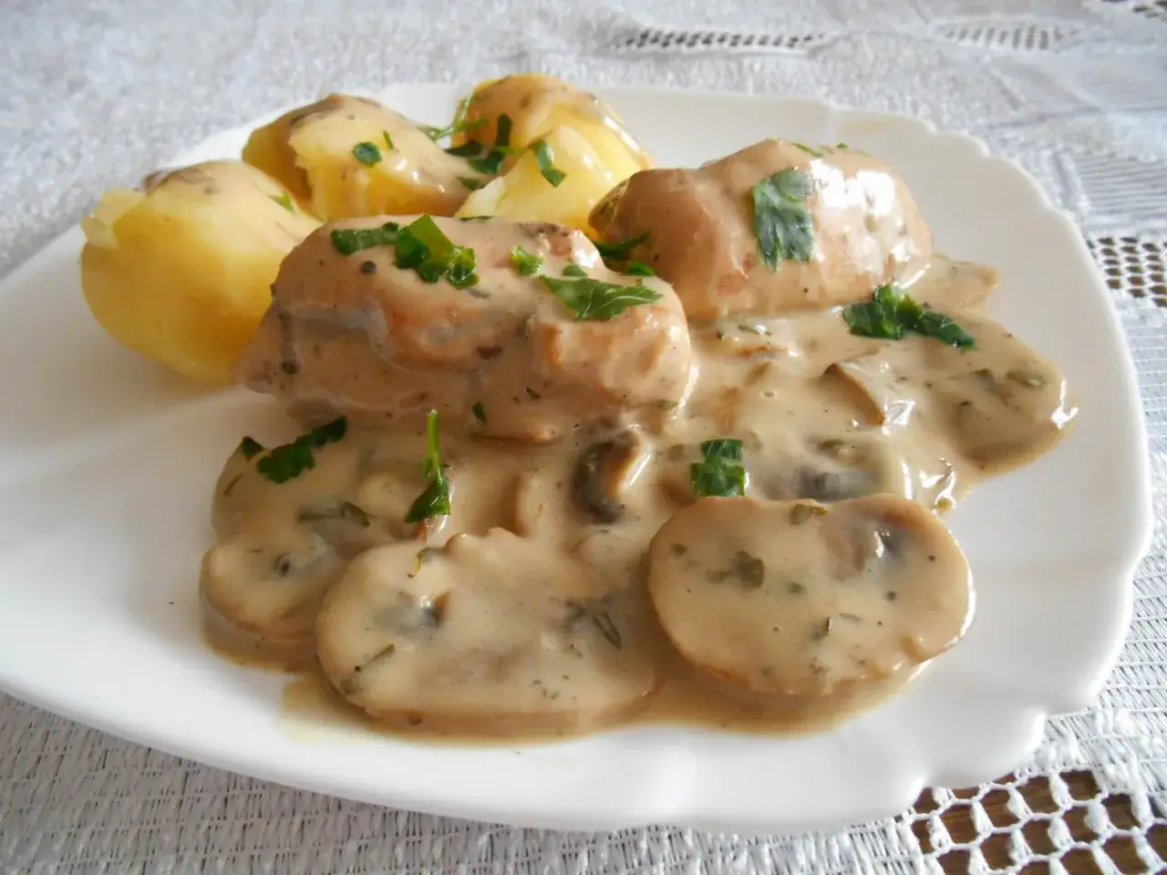 Pyszny kurczak w sosie pieczarkowym z ziemniakami, posypany świeżą natką pietruszki. Idealny obiad.