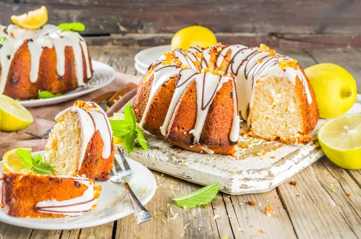 Pyszna babka na oleju z cytrynową polewą i kandyzowanymi skórkami, udekorowana miętą.