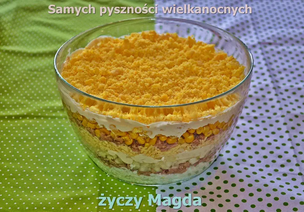 Pyszna sałatka warstwowa z tuńczykiem, kukurydzą i jajkiem, posypana startym żółtkiem. Idealna na wielkanocny stół.