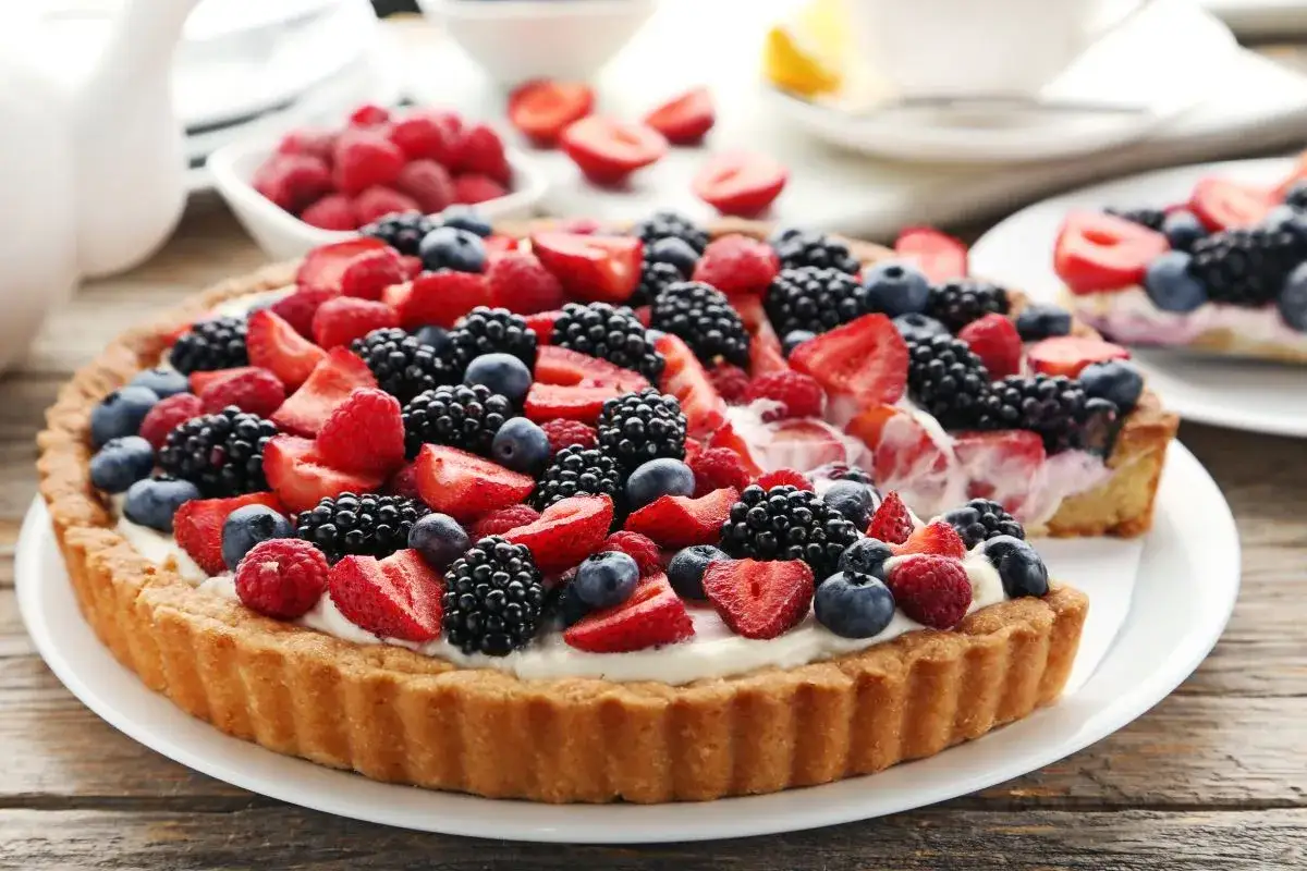 Pyszna tarta z mascarpone, udekorowana świeżymi malinami, borówkami i jeżynami. Idealna na letnie popołudnie.