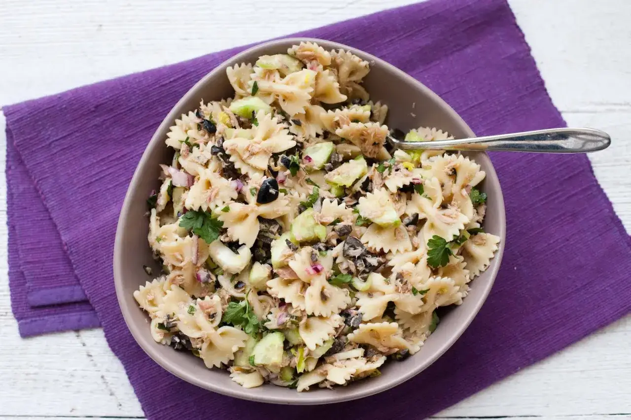Pyszna sałatka z tuńczykiem i makaronem farfalle, z dodatkiem ogórka, oliwek i cebuli. Idealna na szybki lunch.