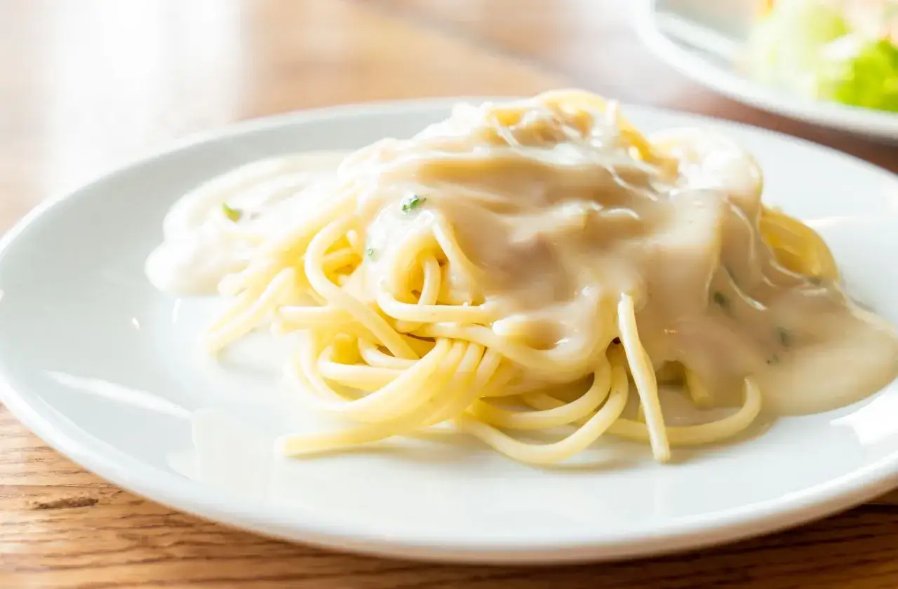 Pyszny makaron spaghetti polany kremowym sosem serowym, gotowy do zjedzenia.