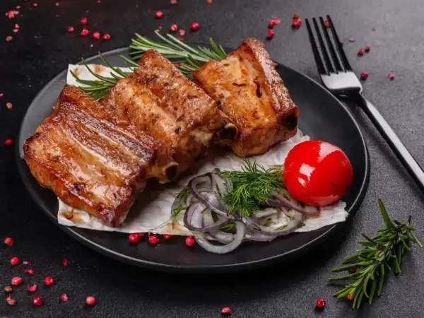 Soczyste żeberka w marynacie, podane z pomidorkiem i ziołami. Idealne na grilla!