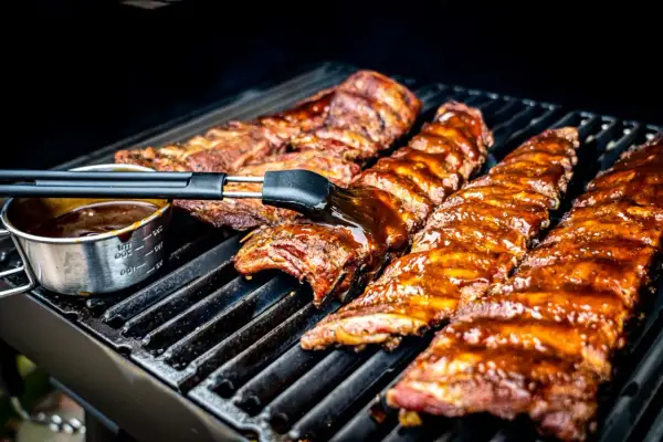 Pyszne żeberka z grilla pokryte sosem BBQ, pędzelkiem smarowane, kuszą apetycznym wyglądem.