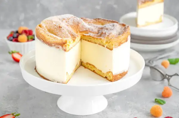 Puszysty kremowy tort, jeden z 10 najlepszych ciast, z ciastem ptysiowym i owocami w tle.