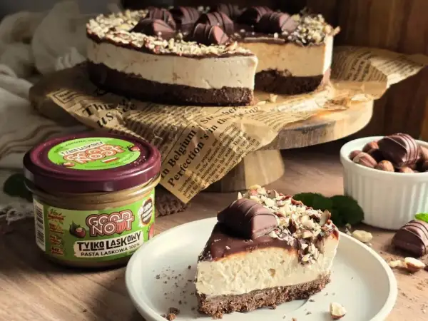Pyszne ciasto Kinder Bueno z kremem i orzechami, obok słoik pasty z orzechów laskowych.