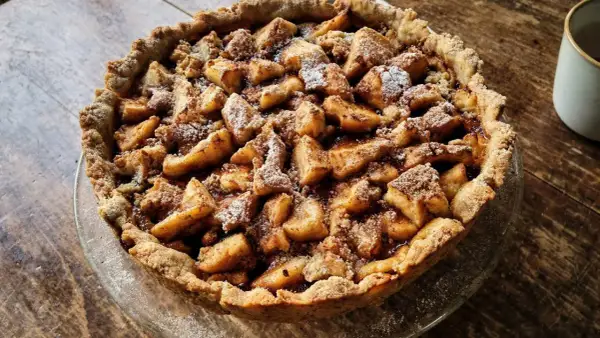Apetyczna tarta na słodko z jabłkami i kruszonką, posypana cukrem pudrem. Idealna na deser.