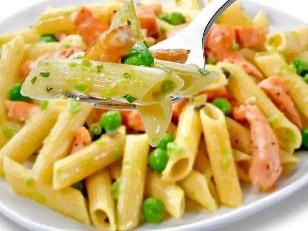 Penne z łososiem wędzonym i groszkiem na widelcu. Pyszne danie, które zachwyci każdego smakosza.